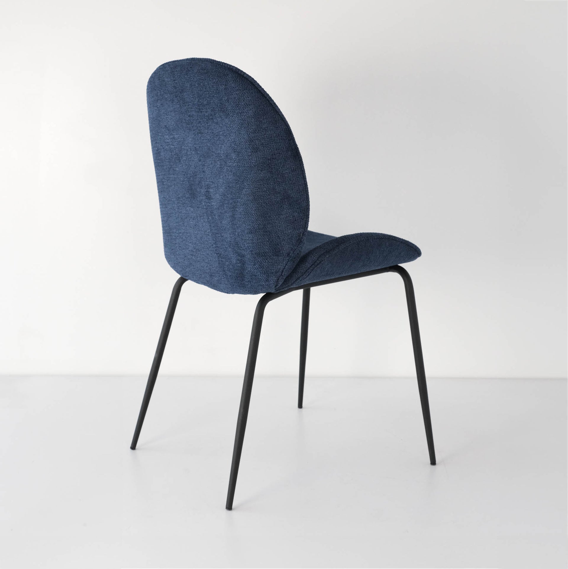 Side-back view of a vibrant royal blue Beetle dining chair
