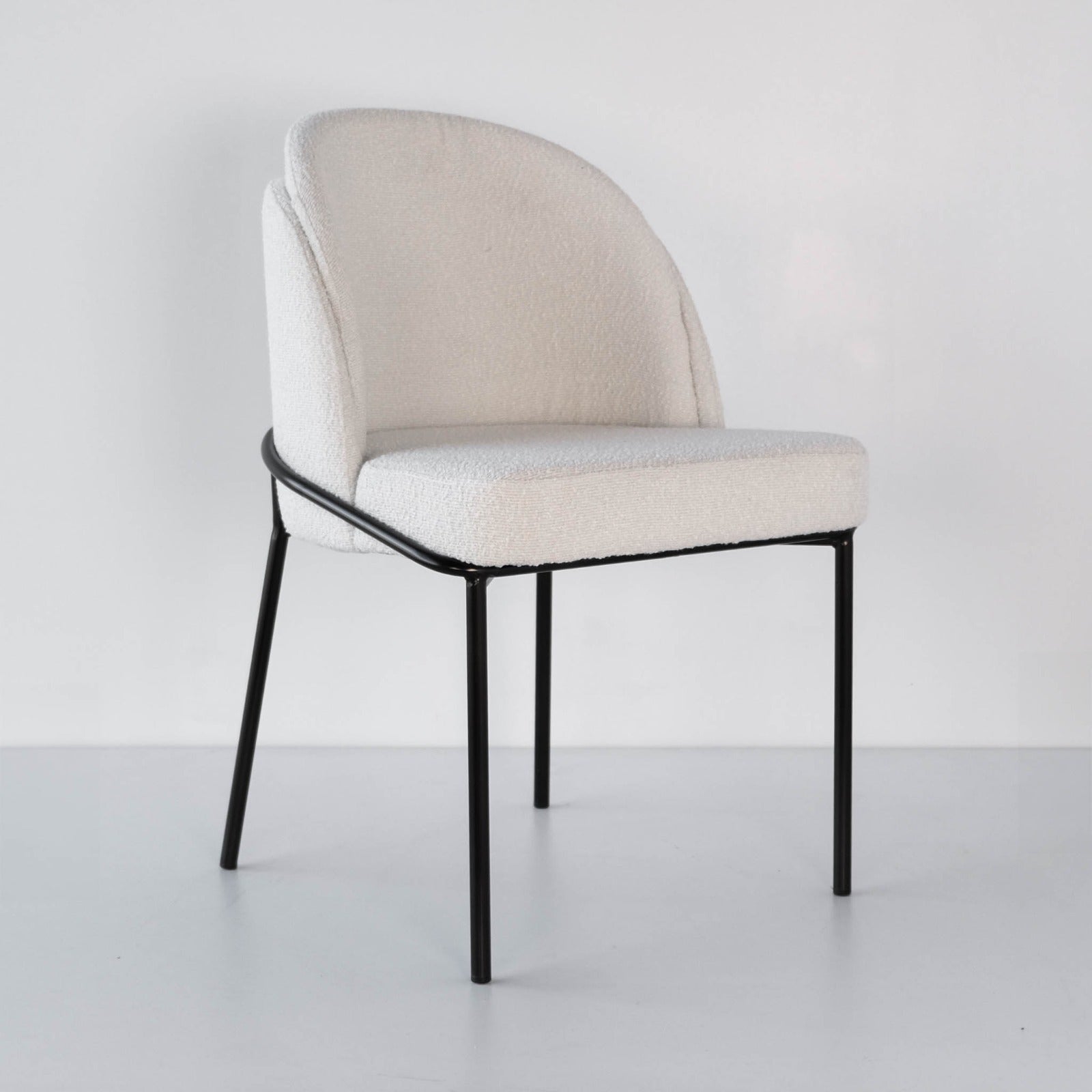 Angle view of a modern boucle dining chair, showcasing its elegant design and textured fabric