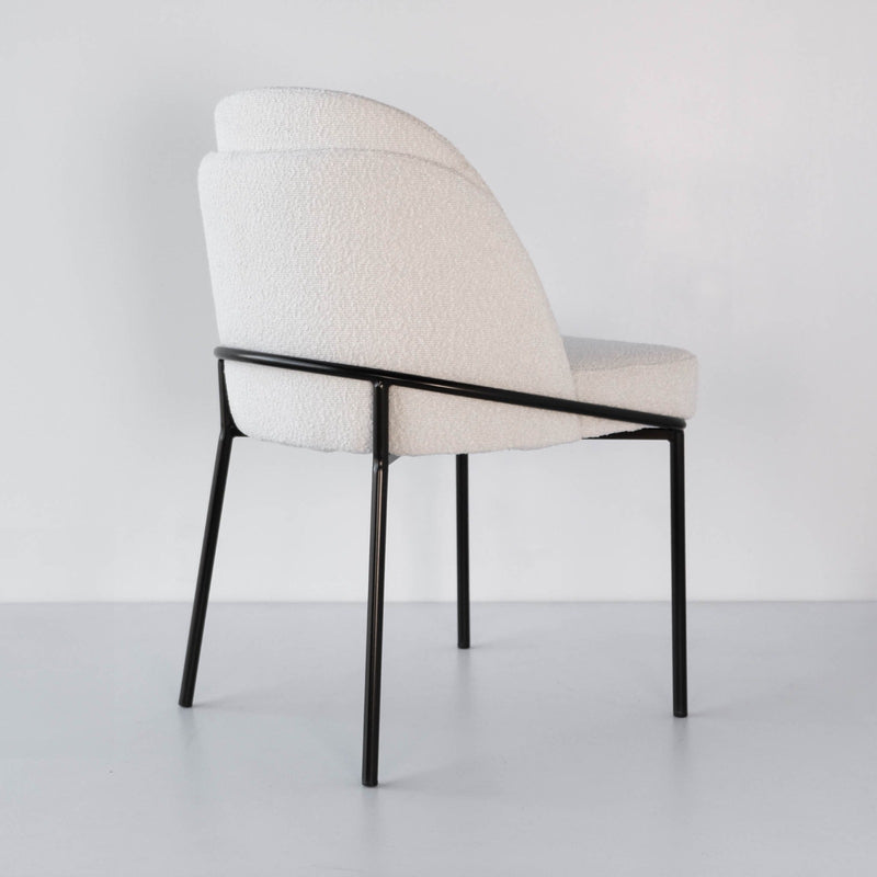 Back view of a textured boucle dining chair with a bronze frame