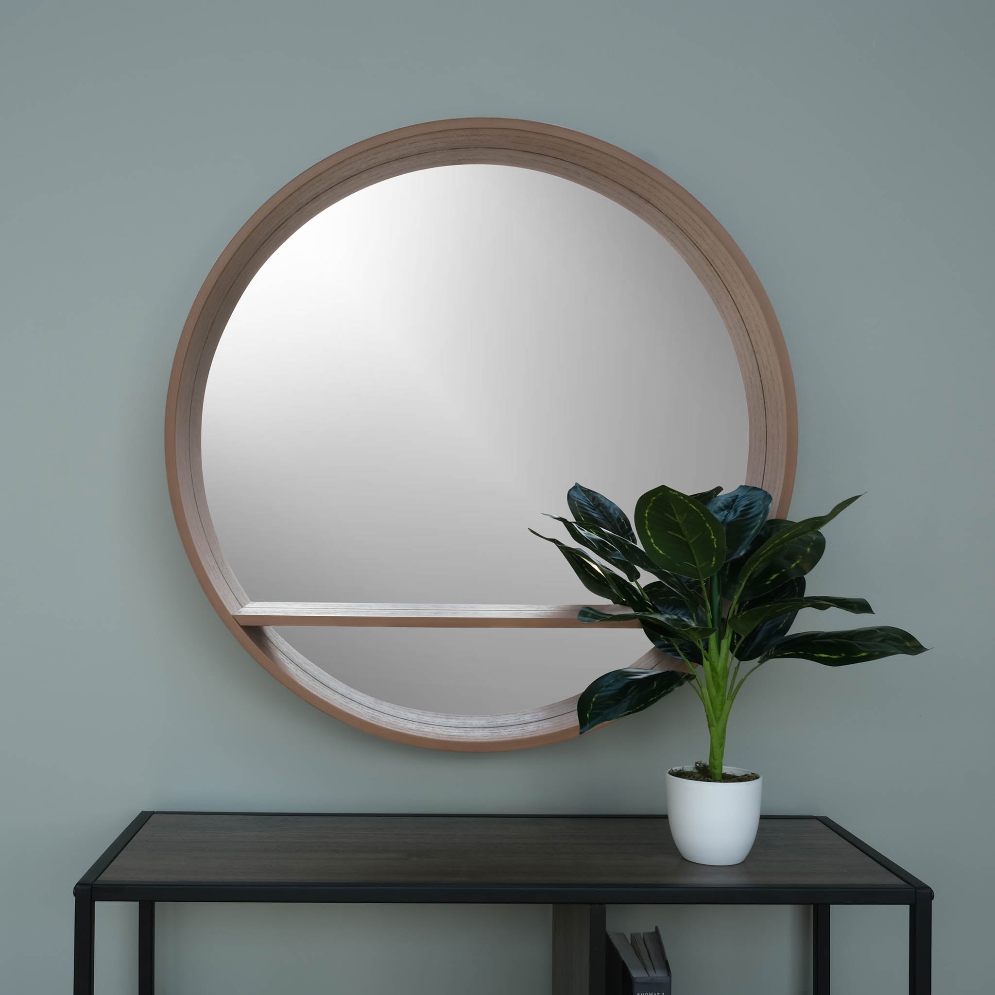 round shelf mirror in pear in a room with a shelf and plant front view