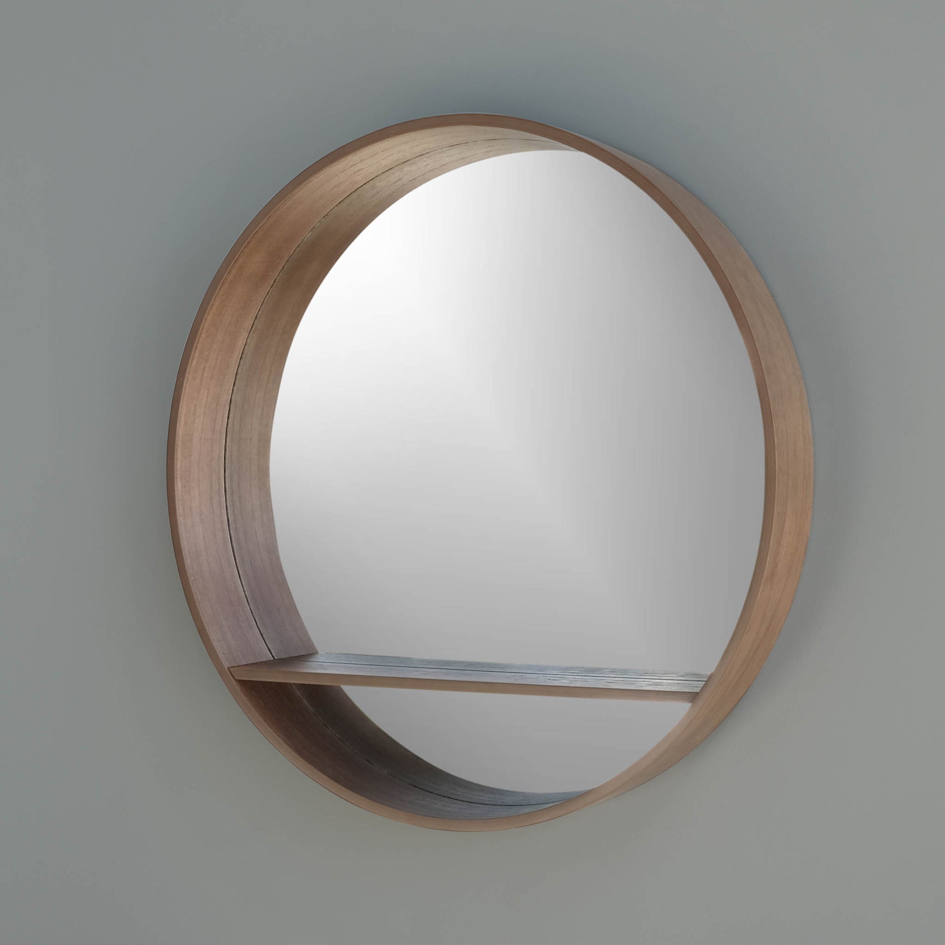 Side view of round mirror with a shelf in pear on a wall