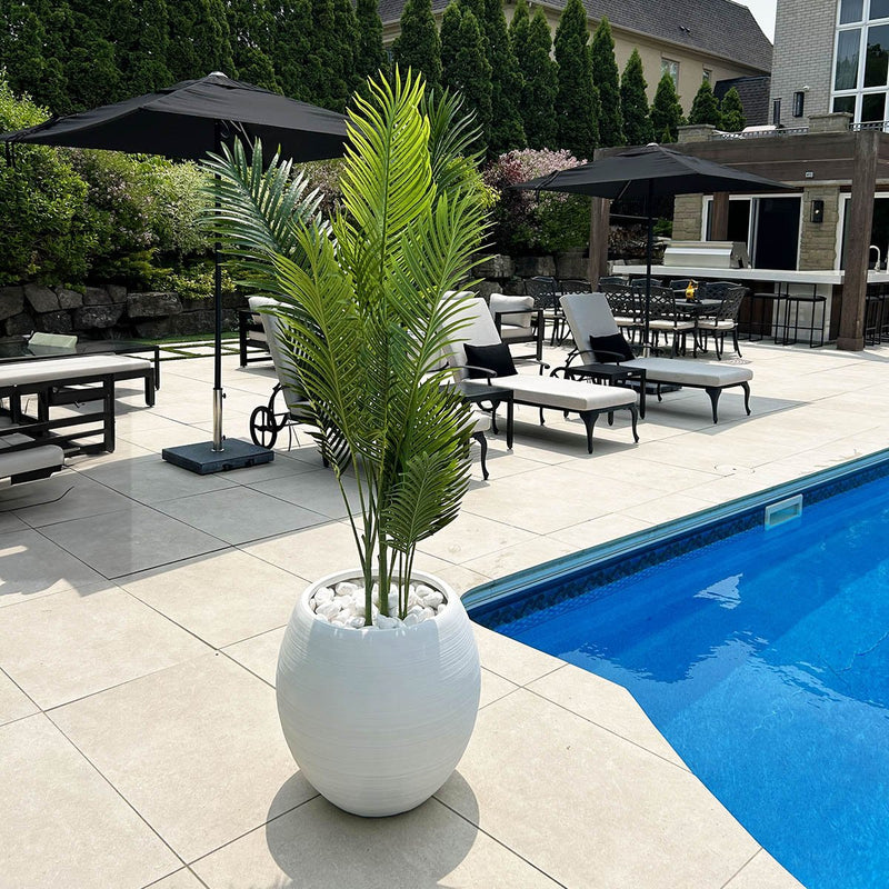 White fiberglass spehrical planter beside a pool